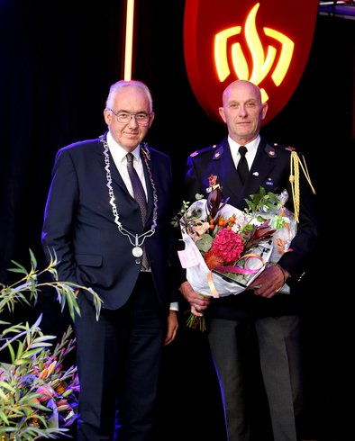 Loco-burgemeester Nees van Wolfswinkel met Bert Spronk voor het logo van de brandweer