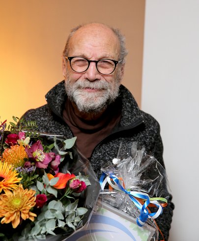 De heer P. Uijl uit Kesteren met de opgespelde Neder-Betuwe Speld en een boeket bloemen