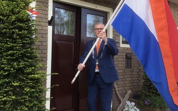 Burgemeester Kottelenberg houdt de Nederlandse vlag omhoog