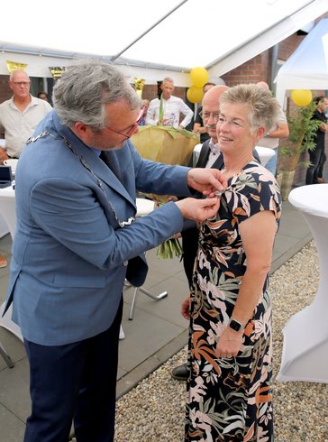 Burgemeester Jan Kottelenberg speldt de Neder-Betuwe speld op bij mevrouw Budding-van Wijk