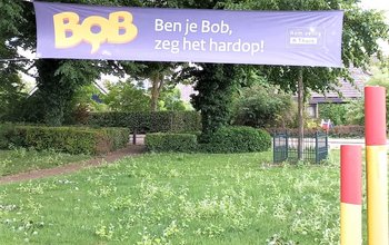 BOB-banner tussen twee bomen boven een grasveld
