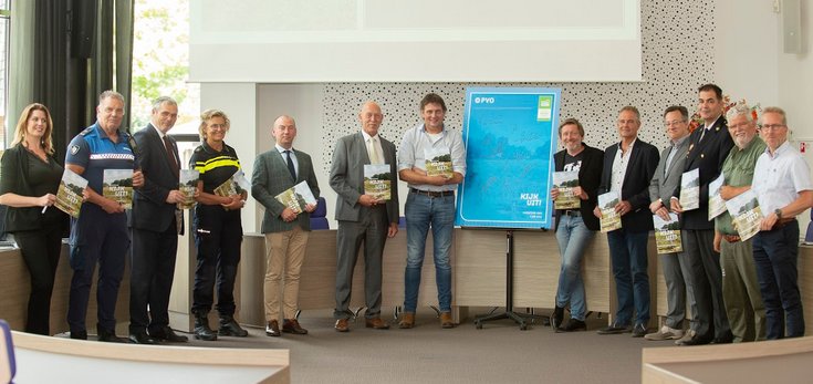Vertegenwoordigers van de veertien gemeenten en de partners die samenwerken voor een Veilig Buitengebied in Gelderland-Zuid bij het bord waar zij hun handtekening op hebben gezet