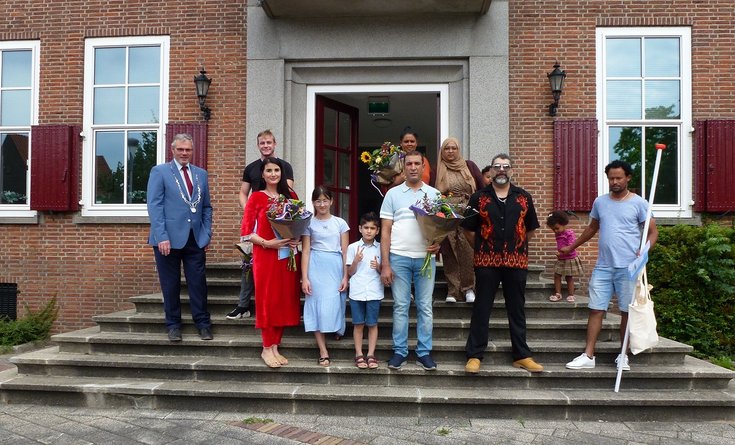 Burgemeester Kottelenberg staat op de trap van het gemeentehuis met de elf inwoners die op donderdag 30 juni de Nederlandse nationaliteit kregen tijdens een feestelijk ceremonie